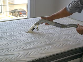 Professional cleaner using steam cleaner on mattress