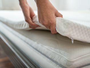 Woman adjusting mattress topper on mattress