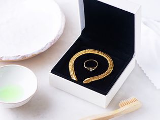 Gold bracelet and ring in black encased box next to tooth brush and dishwashing liquid